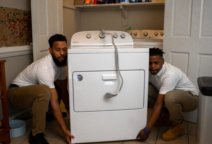 Junk removal professionals lifting a washer and dryer from a foreclosed property